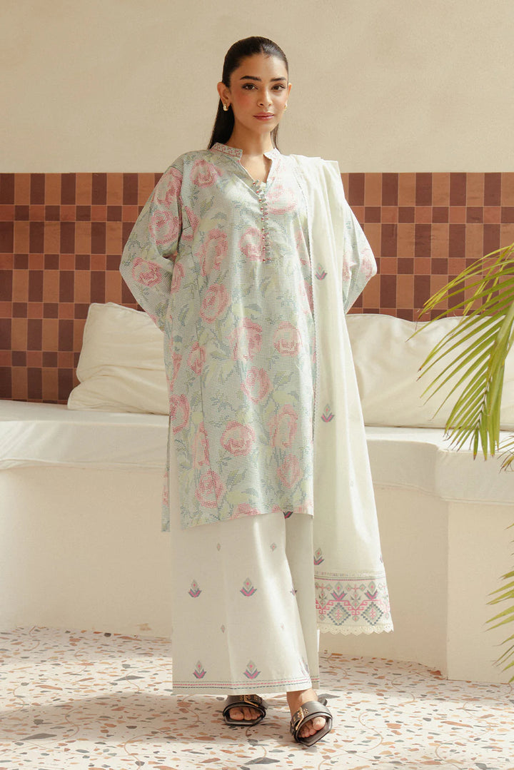 Model stands in Pastel Blush—soft floral lawn shirt with tonal embroidery, white trousers with hem detailing, and a voil dupatta draped with ease.
