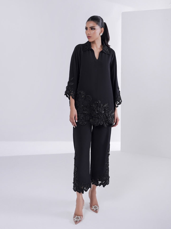 Model wears Alvena from Thea Edit ’25: a black two-piece set with hand-beaded appliqué and cutwork detailing on the shirt hem, sleeves, and culottes.
