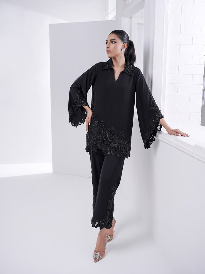 Alvena black set with hand-beaded cutwork on shirt and culottes, styled with embellished heels in a minimalist white space.