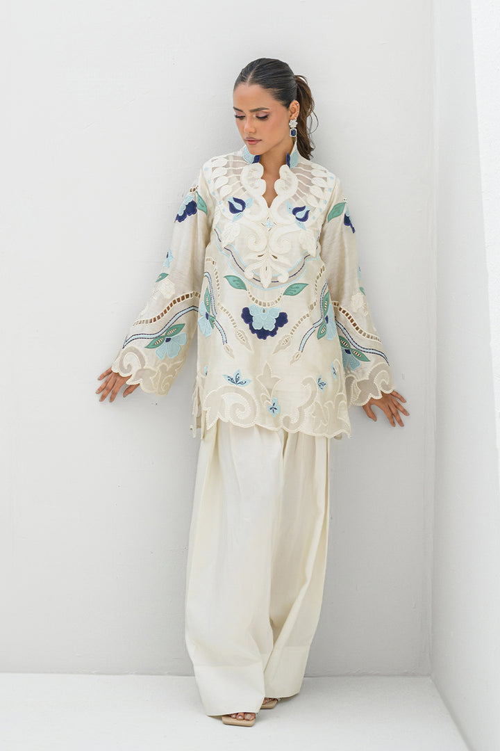 Model presenting Nadia Farooqui Azure off-white short top with blue and teal embroidery and pleated trousers from Deena Eid Edit '25 collection