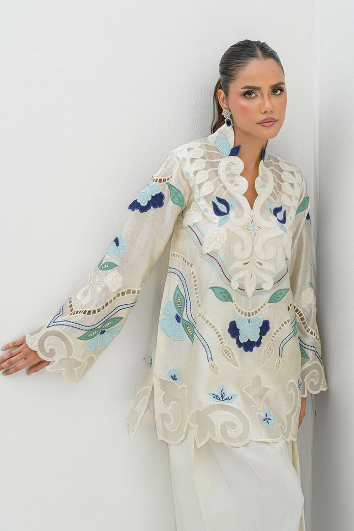 Model in Nadia Farooqui Azure off-white short top with prominent blue and green floral design and white trousers from Deena Eid Edit '25 collection