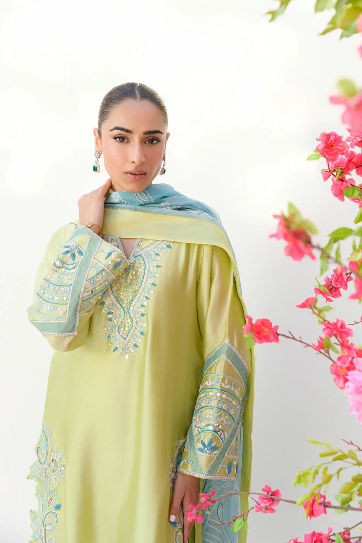 The model wears Mint Margarita: a lime-kiwi Sheesha silk shirt with intricate embroidery along the neckline and sleeves, paired with a matching blue and green organza dupatta draped over one shoulder.