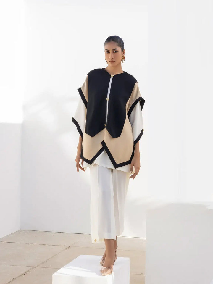 Model showcases Iqa Raya: an ivory geometric top layered on a white kurti & wide-leg pants. Nyra '24, for modern Indian style.
