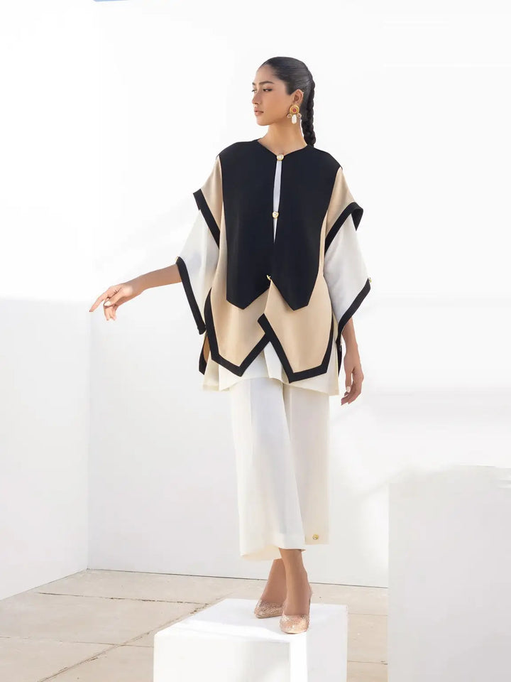 A model poses in Iqa Raya's striking black & beige layered geometric top, paired with a white kurti & wide-leg pants.