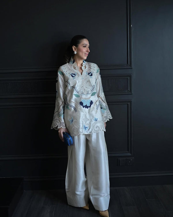 Model showcasing Nadia Farooqui Azure off-white short top with intricate blue embroidery and open shalwar, from Deena Eid Edit '25 collection