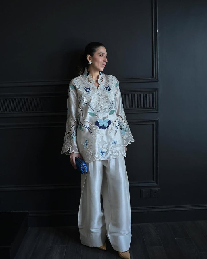 Model showcasing Nadia Farooqui Azure off-white short top with intricate blue embroidery and open shalwar, from Deena Eid Edit '25 collection